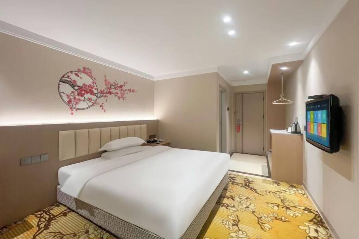 Habitación de hotel con cama, televisor montado en la pared y un adorno decorativo.