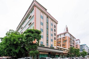 A multi-story hotel with a prominent entrance, surrounded by parked cars and trees. - Kaiping Fujing Hotel (Kaiping)