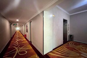 A hotel corridor with carpeted floors, doors, and a visible elevator. - Kaiping Fujing Hotel (Kaiping)