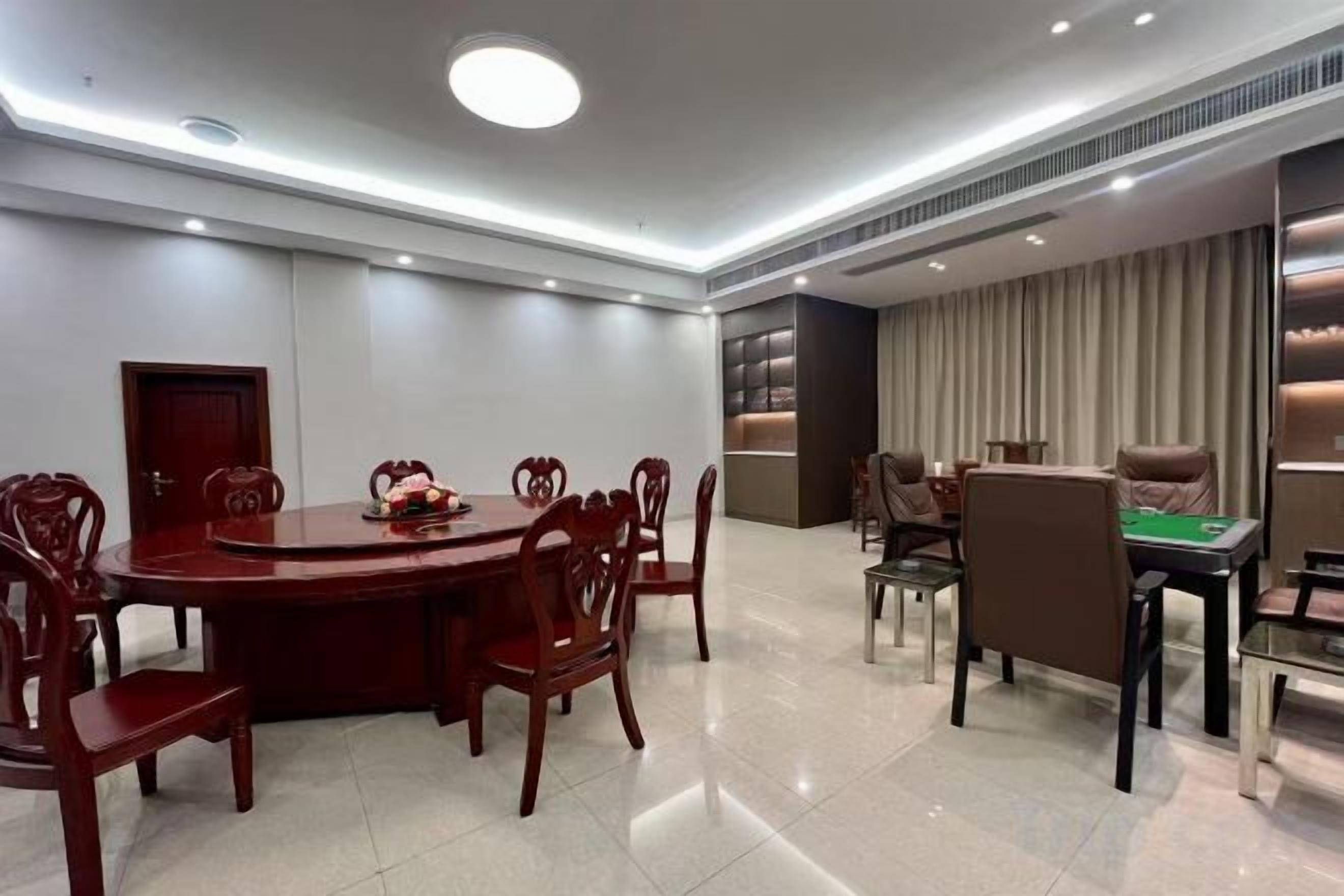 Un salón de conferencias con una mesa redonda, sillas y una mesa de juegos separada con sillas.
