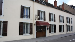 A hotel with a sign, a red awning, and a double door entrance.