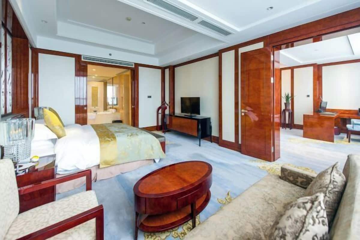 A hotel room with a bed, a desk, a TV, and a sofa.