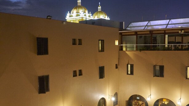 A hotel courtyard with a swimming pool, outdoor seating, and a building with illuminated domes in the background. - Costa del Sol Trujillo Centro (Trujillo)