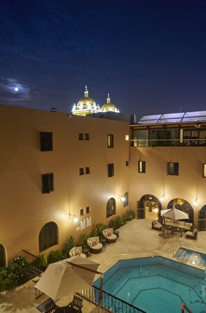 A hotel courtyard with a swimming pool, outdoor seating, and a building with illuminated domes in the background. - Costa del Sol Trujillo Centro (Trujillo)