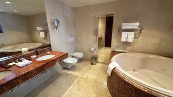 A modern bathroom with two sinks, a toilet, a bidet, and a large bathtub.