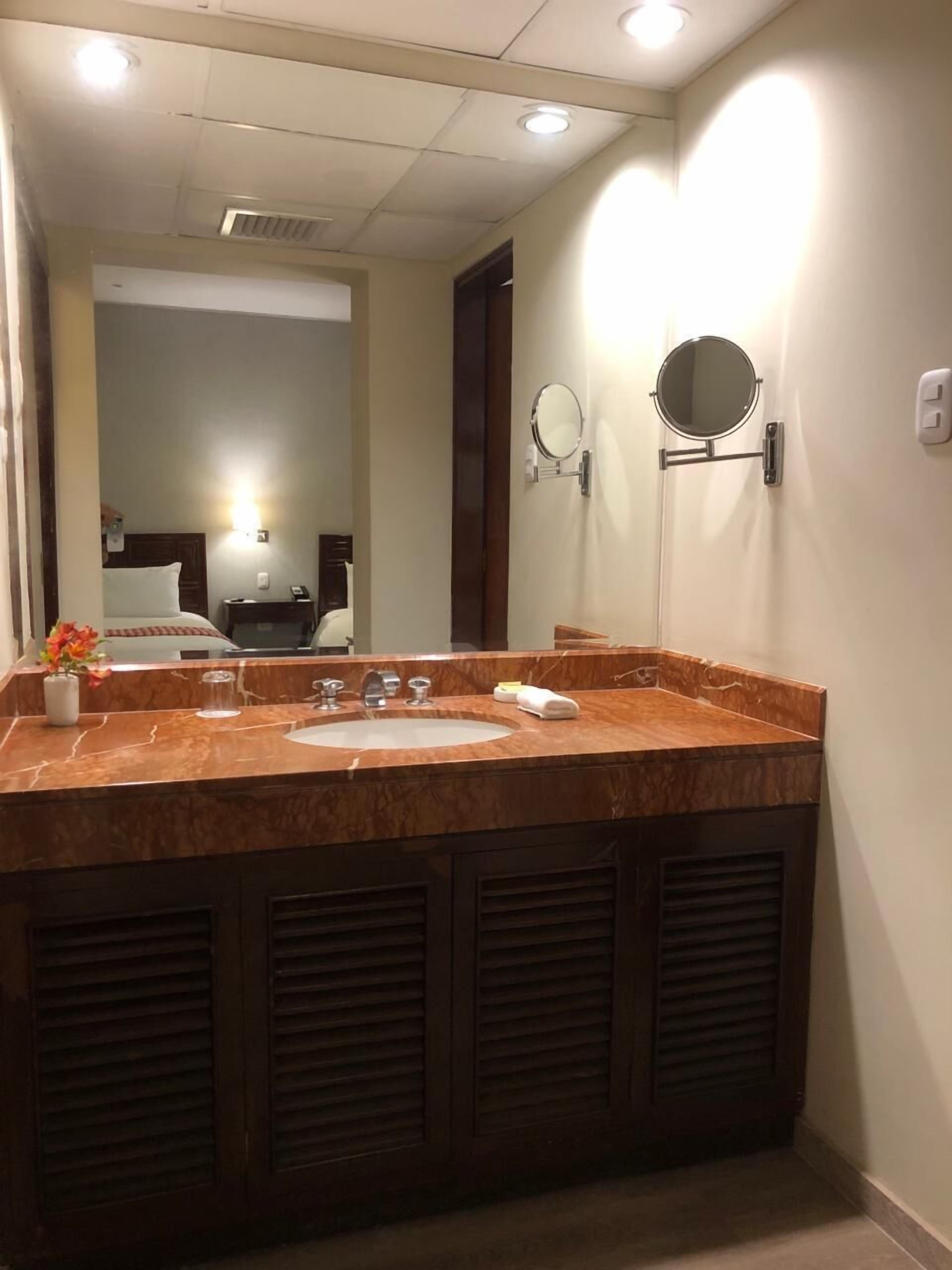 A bathroom with a marble sink, two mirrors, and a vanity.