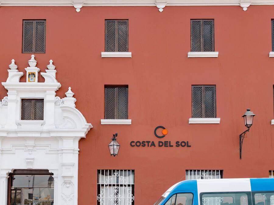 Un bâtiment portant l’inscription « Costa del Sol » et un fourgon bleu et blanc garé devant.