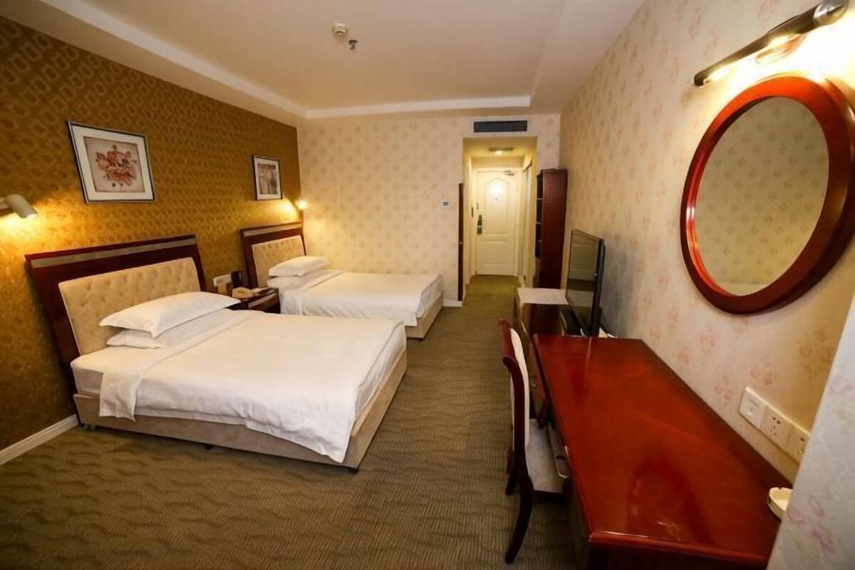 Een hotelkamer met twee bedden, een badkamer en een spiegel.
