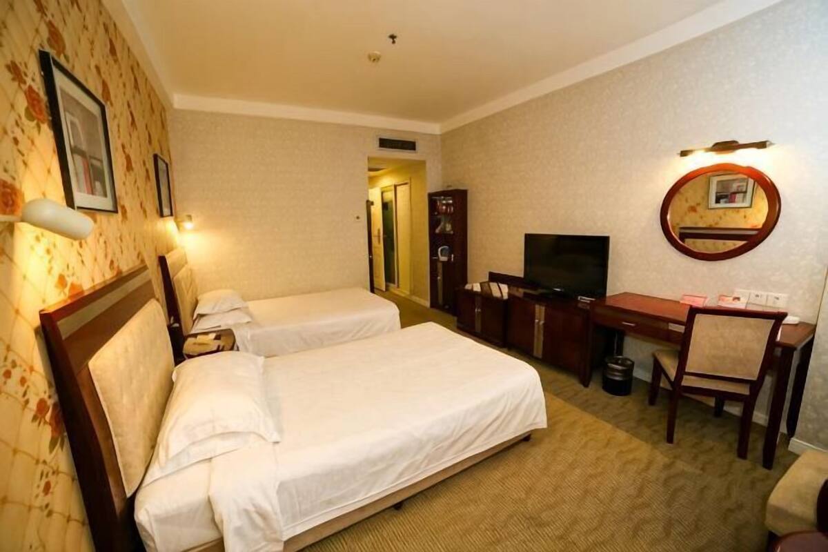 Een hotelkamer met twee bedden, een bureau, een televisie en een spiegel.