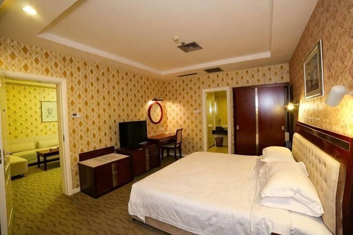 Een hotelkamer met een bed, een bureau, een televisie en een spiegel.