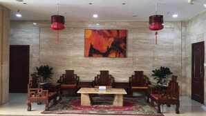 Une salle de conférence avec une table en bois, des chaises, une lampe rouge suspendue au plafond et un grand tableau abstrait accroché au mur.