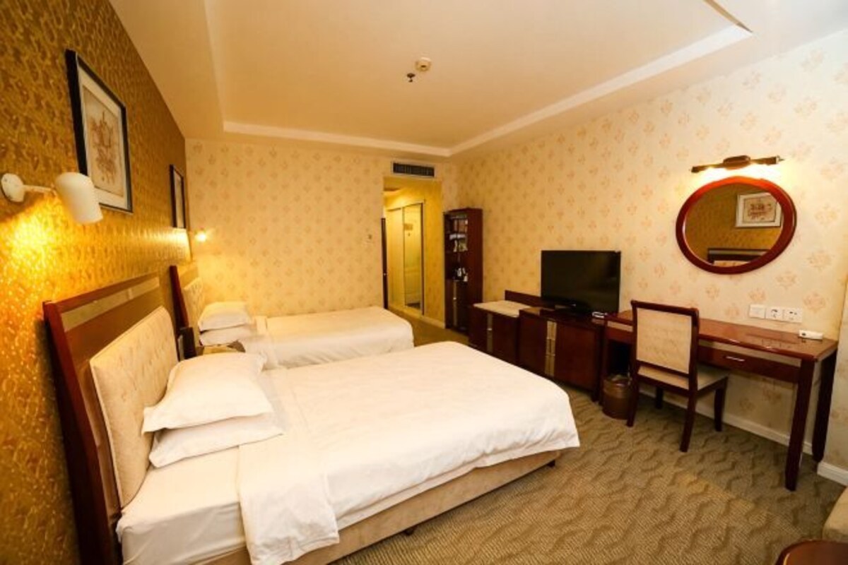 Habitación de hotel con dos camas, un escritorio, una silla, un televisor y un espejo.