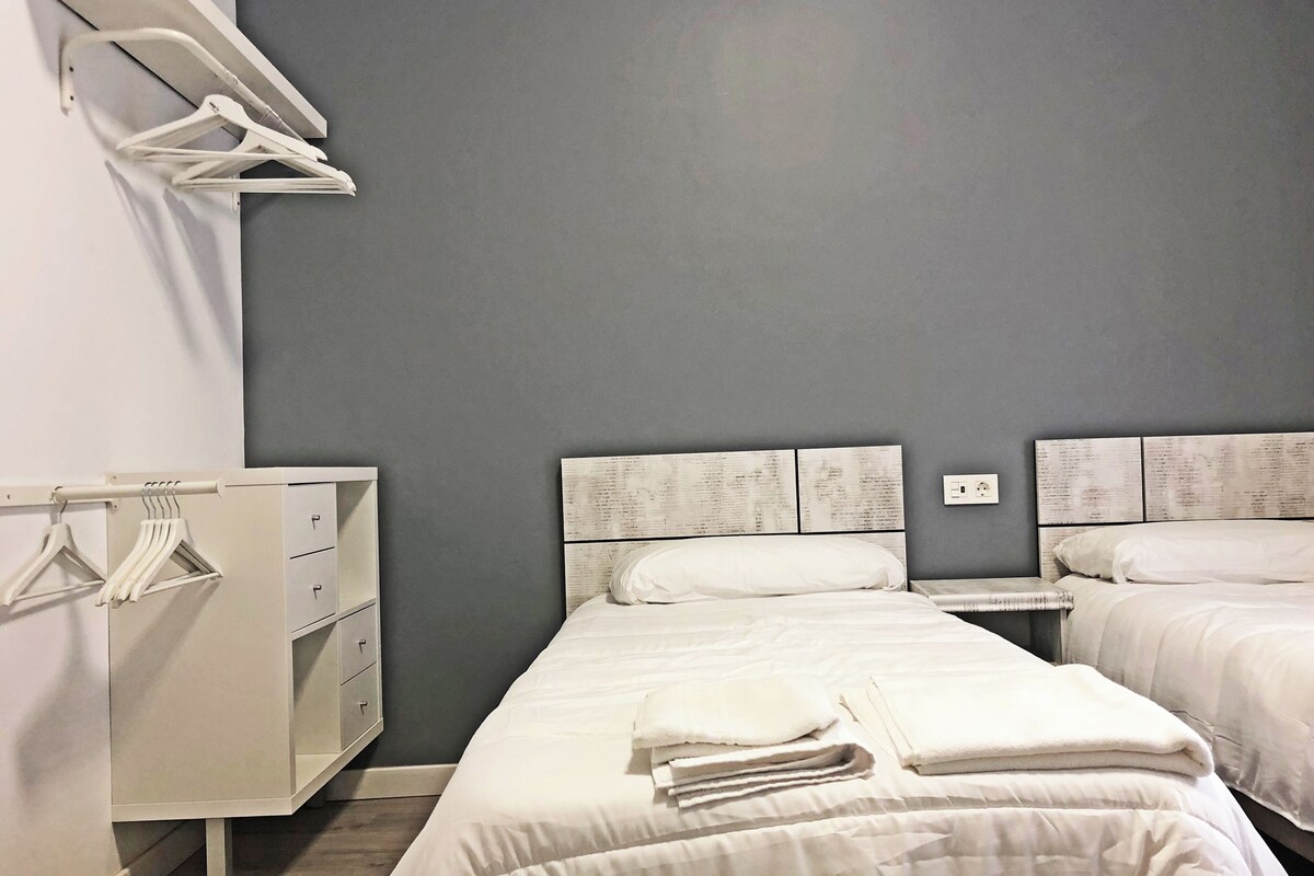 A hotel room with two beds, a wardrobe, and a mirror.