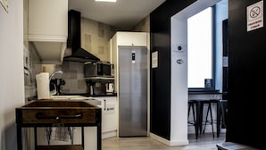A modern kitchen with a stainless steel refrigerator, a microwave, and a wooden table. - Butik Almería Centro (Almeria)