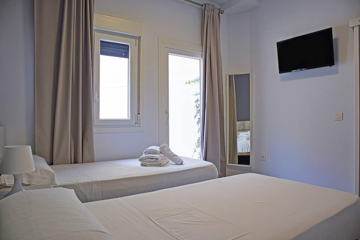 A hotel room with two beds, a TV, and a window with curtains.