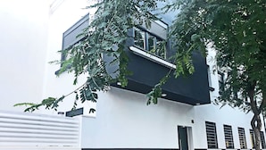 A modern building with a white and black facade, a visible door, and a tree in the foreground. - Butik Almería Centro (Almeria)