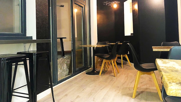 A modern dining area with glass doors, wooden tables, and black chairs. - Butik Almería Centro (Almeria)