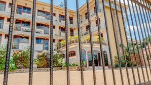 A multi-story hotel with balconies, a paved courtyard, and tropical plants. - Chocolate Luxury Hotel (Kampala)