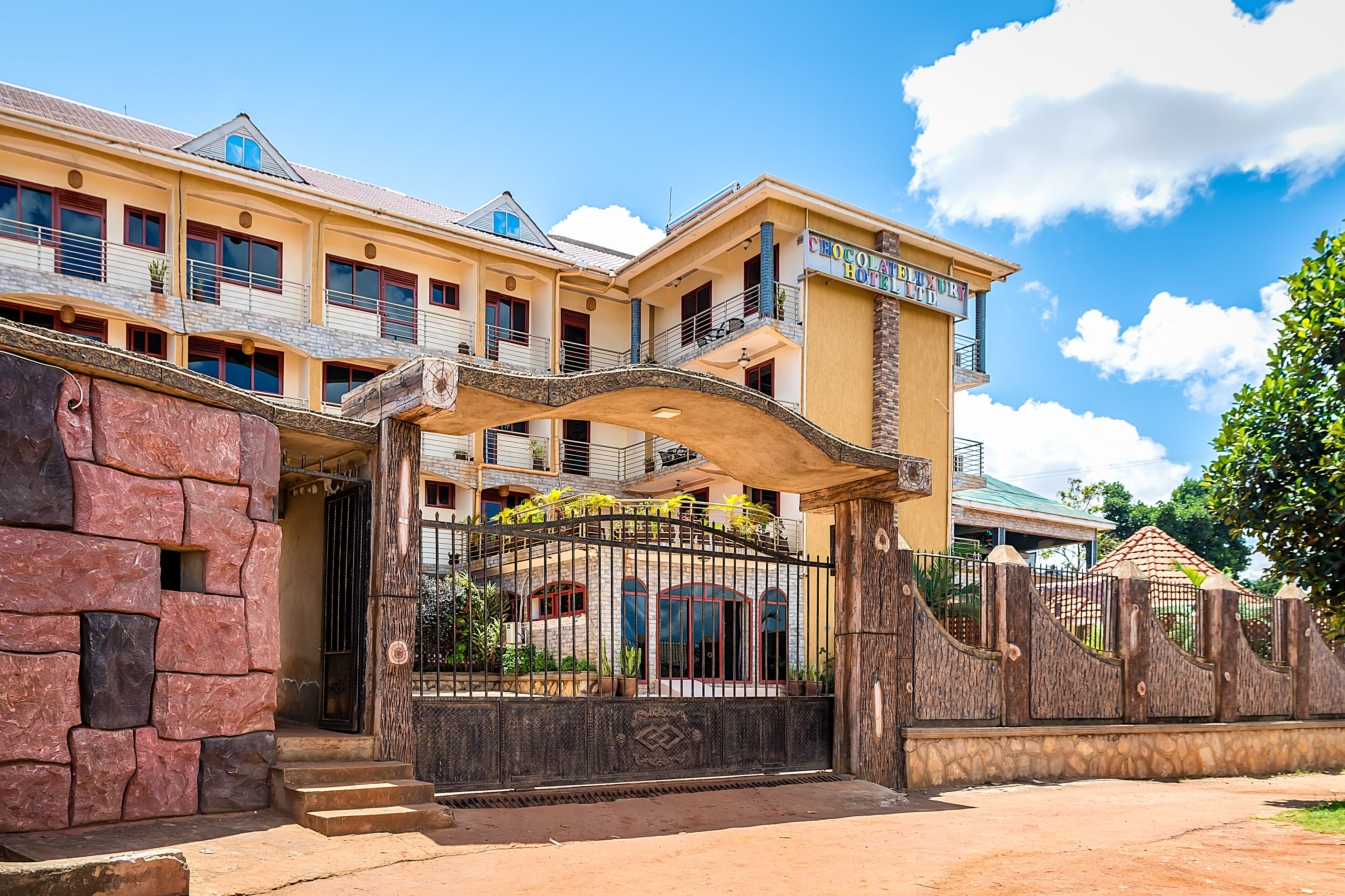 A multi-story hotel with a gated entrance, balconies, and a stone facade.