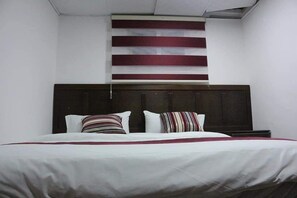 A hotel room with a large bed, dark headboard, and a striped wall decoration. - Moon Valley Camp (Wadi Rum)