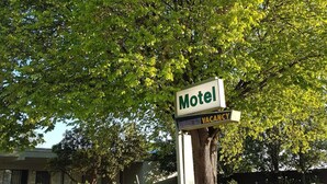 Letrero de motel con un árbol al fondo.