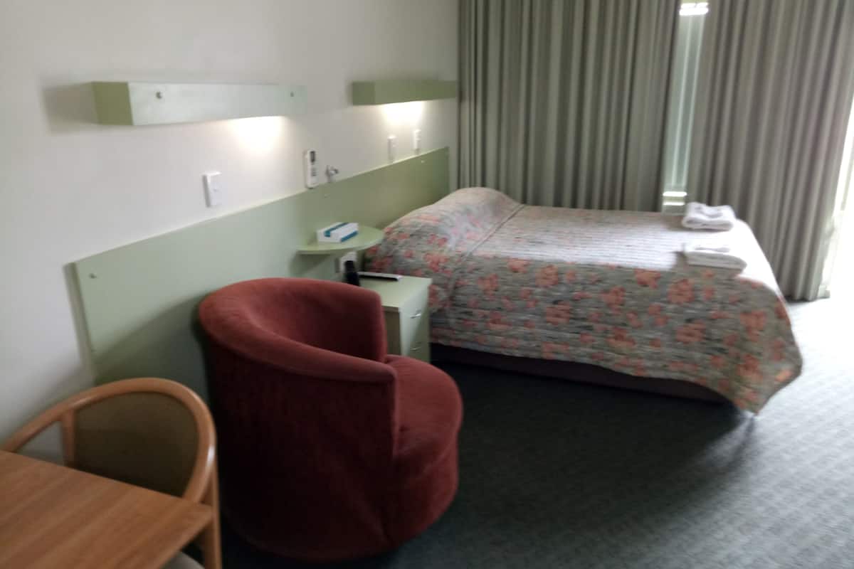 Une chambre d’hôtel comprenant un lit, un bureau, une chaise et une table de chevet.