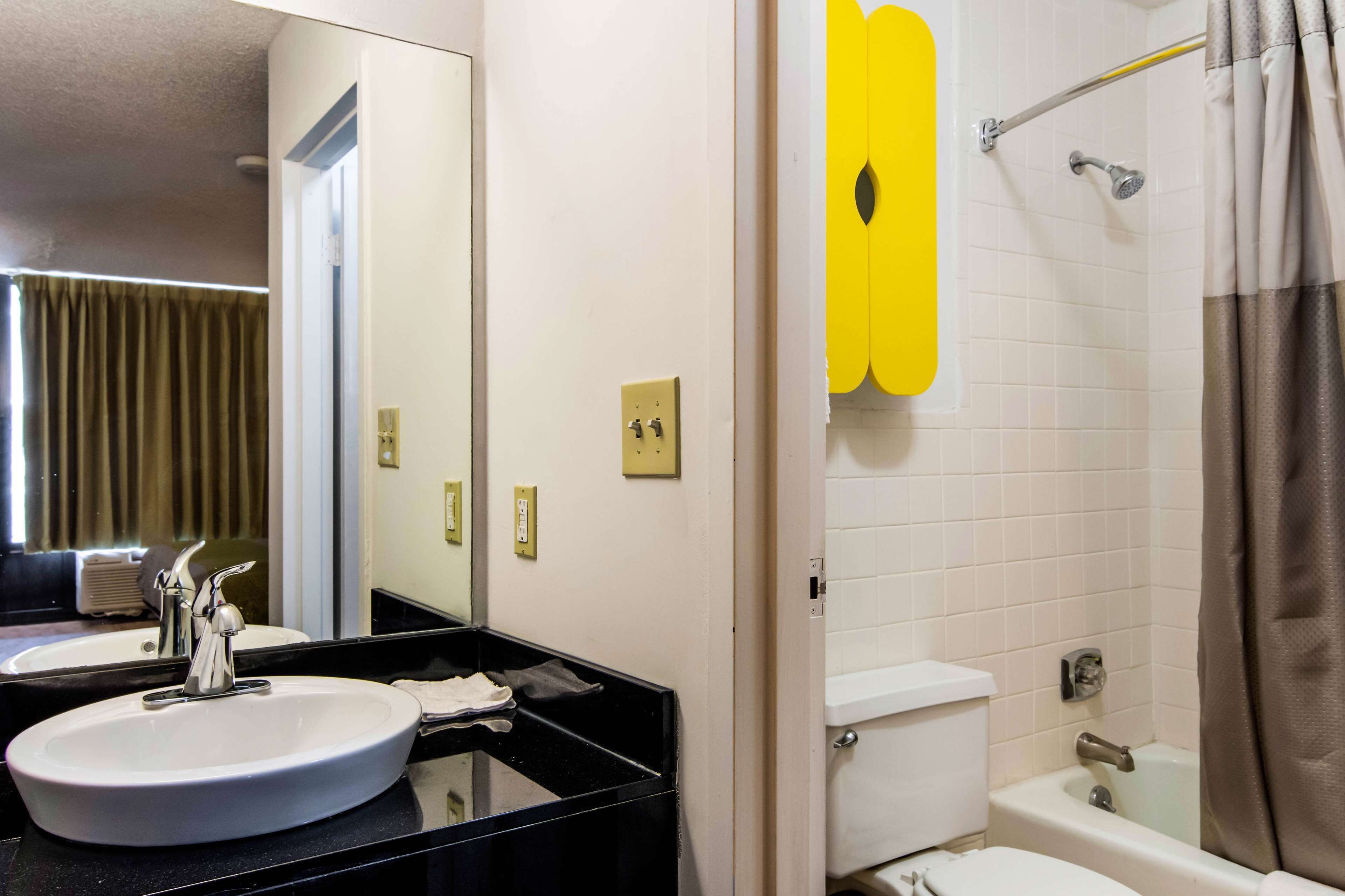 A bathroom with a sink, mirror, toilet, and shower.