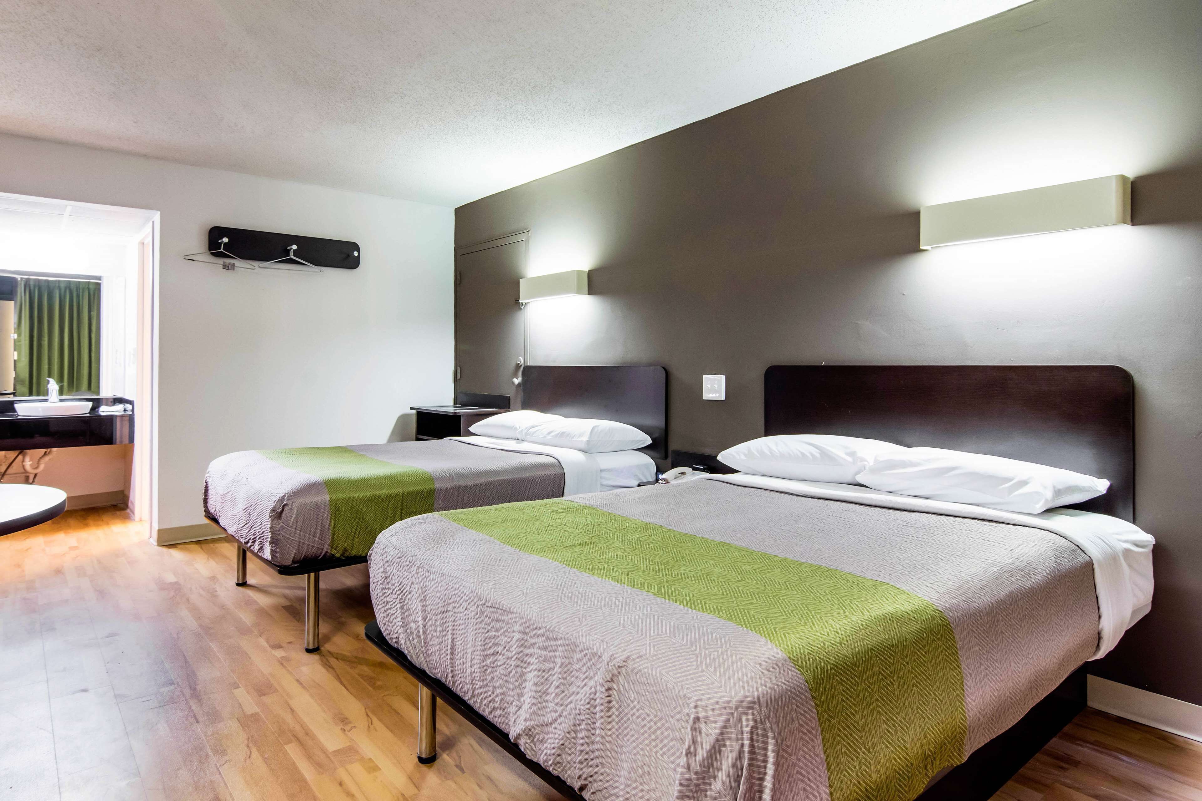 Hotellihuone, jossa on kaksi sänkyä, pieni työpöytä ja ikkuna, jossa on verhot.