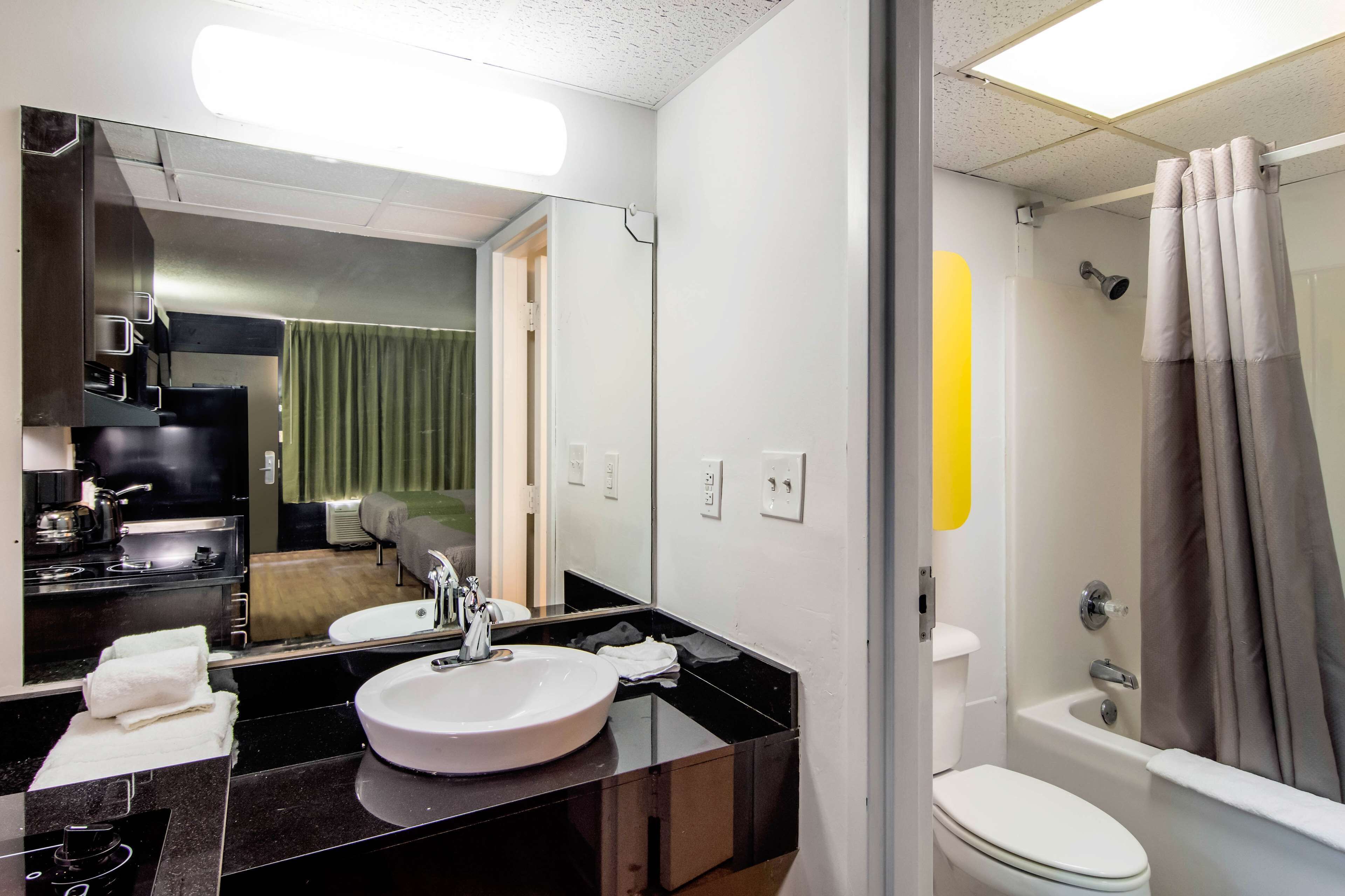 A modern bathroom with a black countertop sink, a mirror, a toilet, and a shower with curtains.
