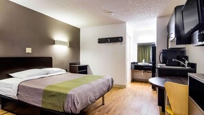Una habitación de hotel moderna con cama, mesita de noche, escritorio, silla y televisor.