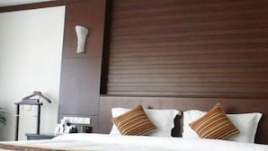 A hotel room with a bed, pillows, a bedside table, and a wall-mounted light fixture. - East Lake International Hotel (Yangjiang)