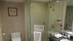 A bathroom with a toilet, a glass shower enclosure, a sink with a mirror, and a towel rack. - East Lake International Hotel (Yangjiang)