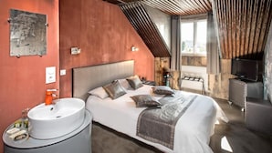 A bedroom with a bed, bedside table, and a mounted television.