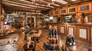 A bar with wooden beams, a chandelier, and a variety of wine bottles and glasses.