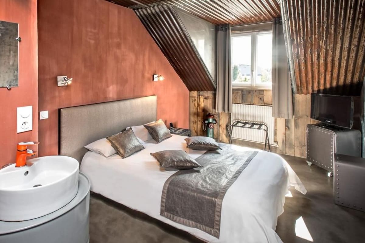 A bedroom with a bed, bedside table, and a mounted television.