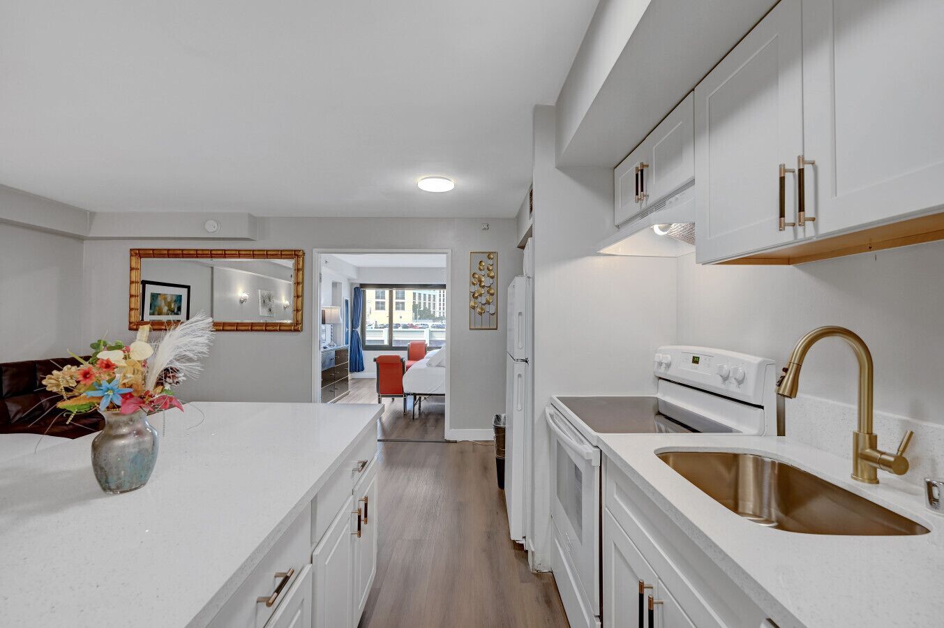 A modern kitchen with white cabinetry, a stainless steel sink, and a white stove.