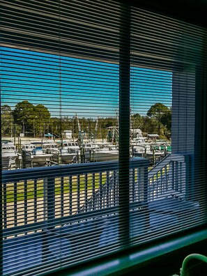 A marina with boats docked, viewed through window blinds.