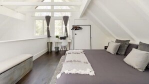A bedroom with a large bed, a desk, and a window with curtains. - Cozy Treetop A-Frame, Fireplace, Arcade Games, Record Player (Lake Arrowhead)