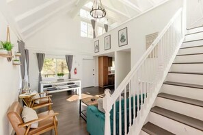 Un vaste espace de vie doté d’un haut plafond, d’un escalier et offrant une vue sur l’extérieur.