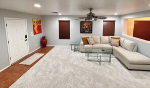 A living room with a sectional sofa, a glass coffee table, a ceiling fan, and a door with a red vase. - Private Hot Tub, Mountain Views, 3BR. 
GREAT Location: Near UA & Biking Paths. (Tucson)
