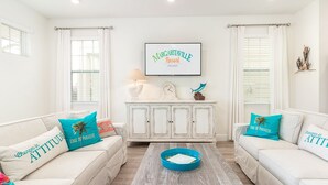 A bright living room with white furniture, a coffee table, and a framed sign on the wall. - Amazing Margaritaville Holiday Home - Indoor/Outdoor Entertaining Space (Kissimmee)