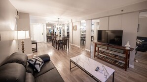 Ein Wohnzimmer mit einer Couch, Couchtisch, Fernseher und einem Essbereich mit Stühlen und Tisch.