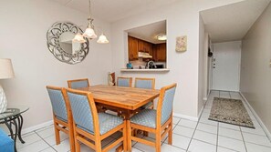 A dining area with a wooden table and six chairs, a decorative mirror, and a hanging light fixture. - Relaxing St. Augustine Beach Retreat – First Floor, Steps to the Sand (St. Augustine)