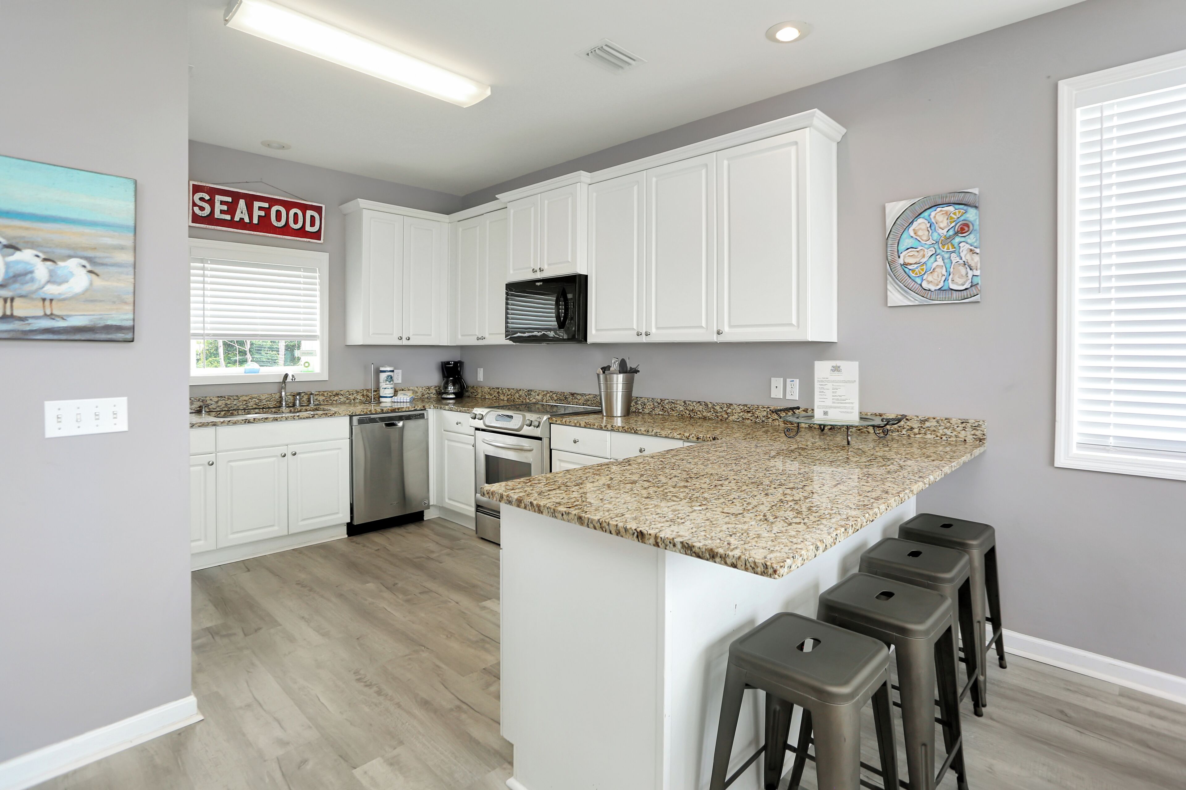 A modern kitchen with white cabinets, granite countertops, and a central island with bar stools.