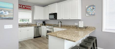 A modern kitchen with white cabinets, granite countertops, and a central island with bar stools.