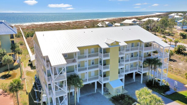 Un hôtel à plusieurs étages doté de balcons donnant sur une plage et l’océan.
