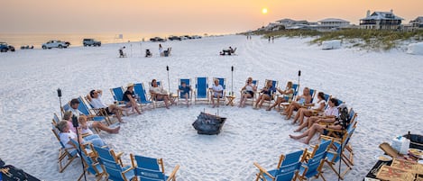 Guests gather around a fire pit on the beach, taking in the ocean views.