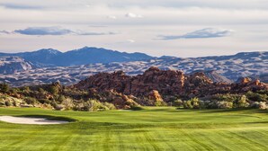 Un parcours de golf avec une chaîne de montagnes en toile de fond et des formations rocheuses.