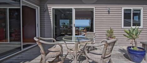 A patio with wicker furniture and a glass table, overlooking a scenic view.