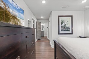 A bedroom with a large bed, a dresser, and a framed picture on the wall.